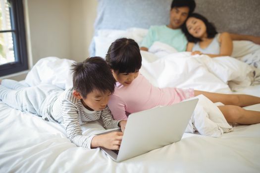 Sibling using laptop in bedroom