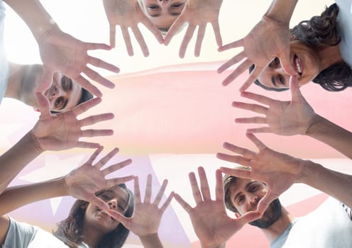 View from below of smiling friends showing their hands