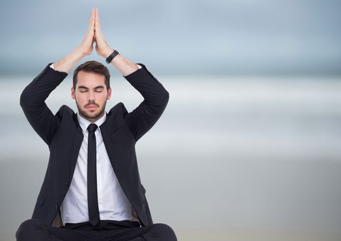 Business man meditating against blurry beach