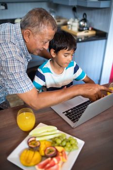 Grandfather assisting grandson using laptop