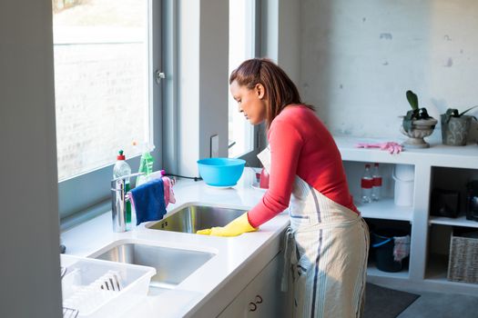 Woman washing utensil in kitchen sink