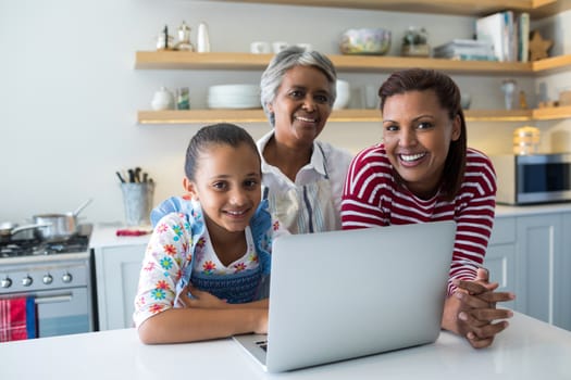 Happy family standing near kitchen worktop with laptop