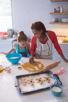 Mother and daughter preparing cookies in kitchen worktop
