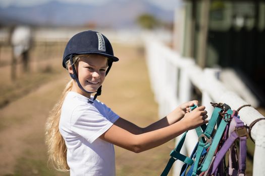 Smiling girl picking up a horse muzzle in the ranch