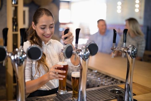 Female bartender filling beer from bar pump