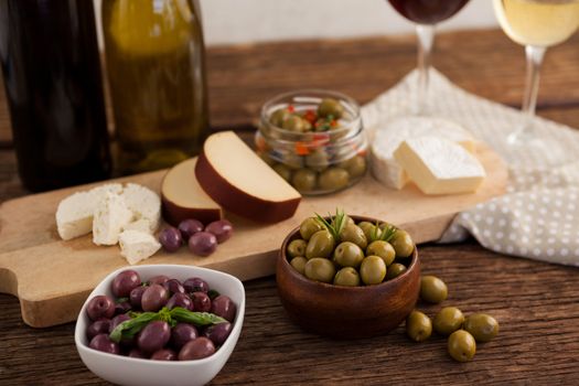 Close up of olives with cheeses and vegetable by wineglass