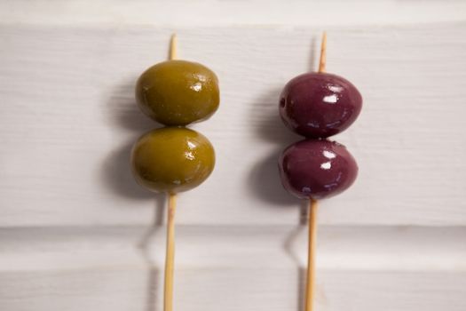 Close up of green and brown olives on toothpick