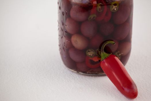 Close up of red olives with jalapeno in glass jar