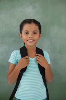Young girl with bagpack against chalk board