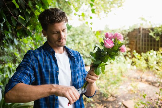 Man trimming flowers with pruning shears in garden