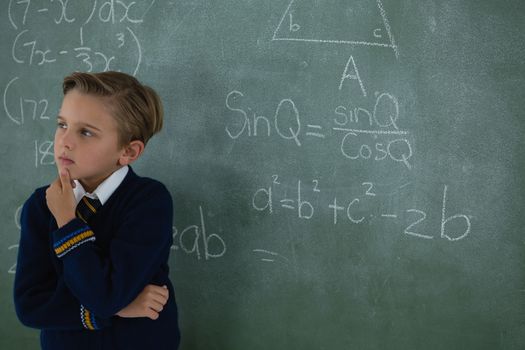 Schoolboy standing against chalkboard