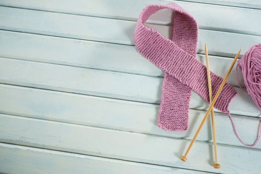 Overhead view of pink woolen Breast Cancer Awareness ribbon with crochet needles