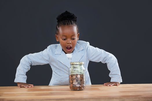 Shock businesswoman looking at coins in glass jar