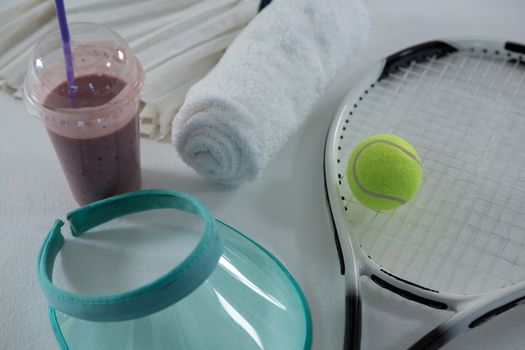 High angle view of racket with sun visor by drink and napkin