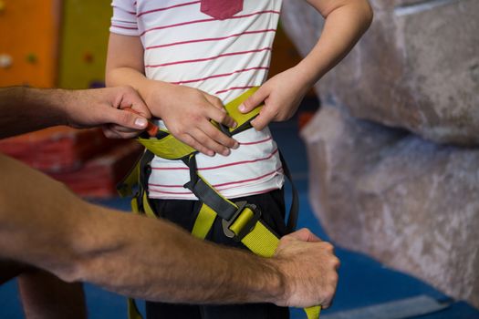 Trainer assisting boy to wear safety harness