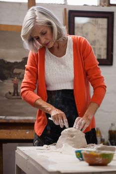 Attentive senior woman shaping a molded clay