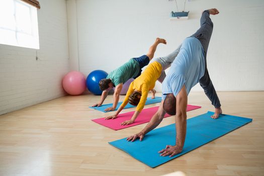 Instructor with students practicing downward facing dog pose with feet up