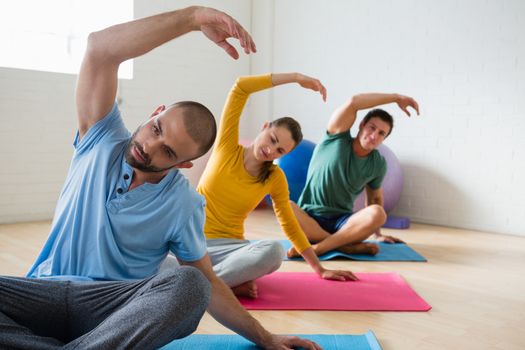 Yoga instructor with students exercising at club 