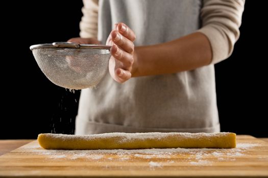Woman icing sugar on dough
