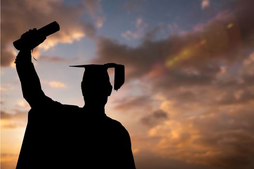 Graduate student raising the diploma against sunset or sunrise