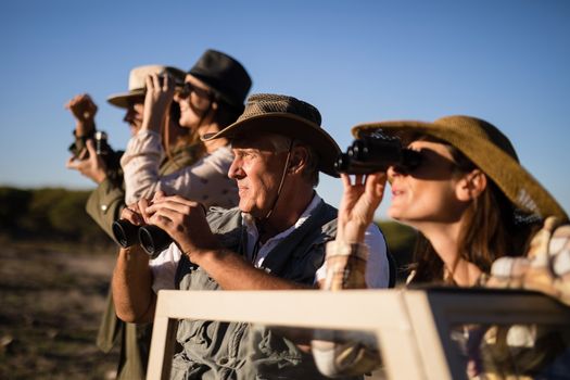 Friends looking through binoculars during safari vacation