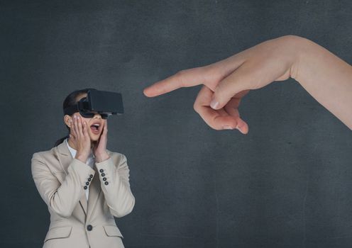 Hand pointing at surprised business woman in a VR headset against blue background