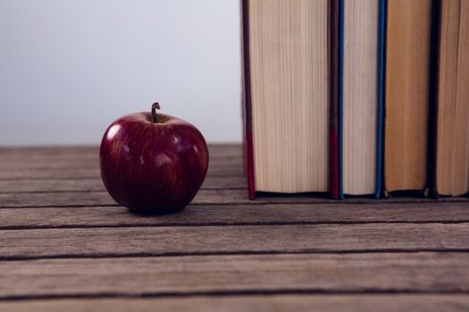 Apple and books arranged on wooden table