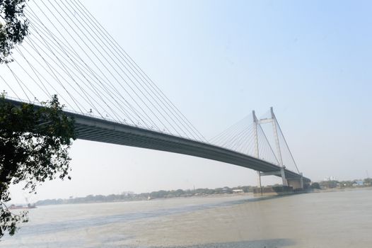 Panoramic Vidyasagar Setu or Hooghly Bridge during sunset. Famous longest cable stayed toll flyover over Ganges River connection cities Kolkata and Howrah. Calcutta West Bengal India South Asia Pac.