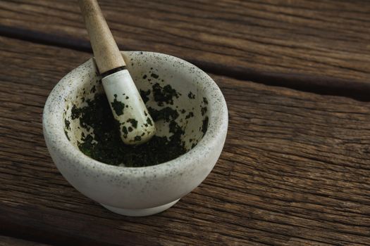 Herb paste in mortar and pestle on wooden table
