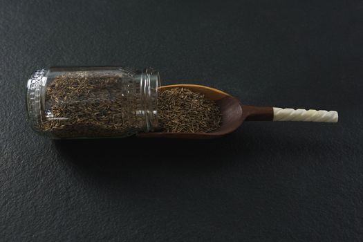 Cumin spilling out of jar into scoop