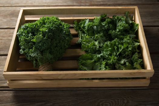 Fresh kale in wooden crate on table