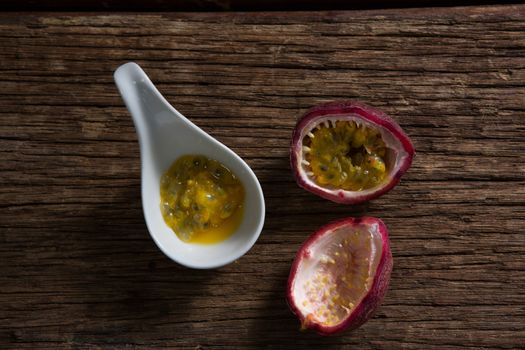 Two passion fruit and spoon with passion fruit pulp on wooden table