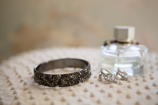 Close up of earring with bangle and perfume bottle