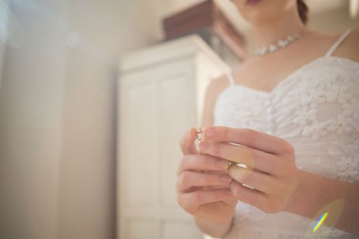 Midsection of bride holding earring at home