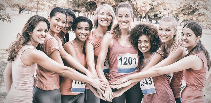 Female breast cancer marathon runners stacking hands 