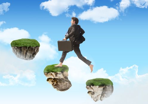Businessman running up steps of floating rock platforms in sky