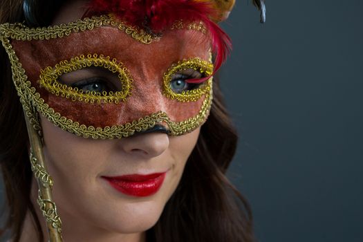 Woman wearing masquerade mask against grey background