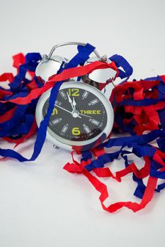 Alarm clock and streamers against white background