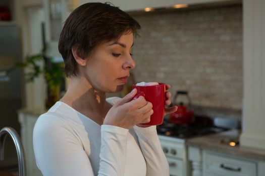 Woman having hot drink in kitchen