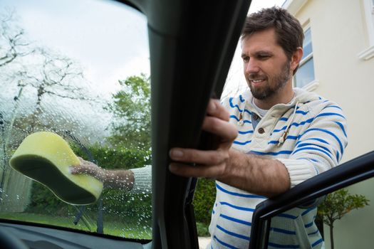 Auto service staff washing a windscreen with sponge