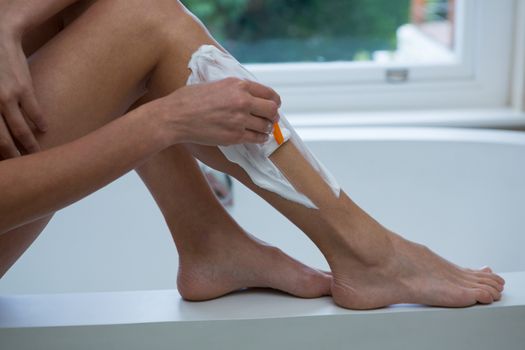 Woman waxing her leg in bathroom