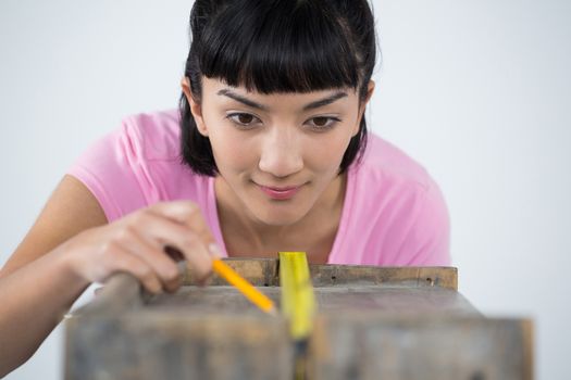 Woman measuring wooden plank with tape measure