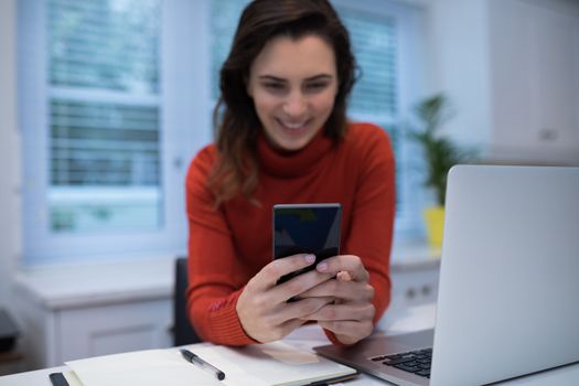 Woman using mobile phone at desk