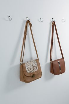 Stylish handbags hanging on hook