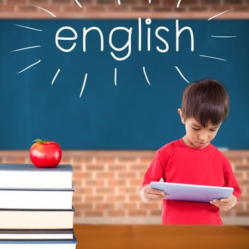 The word english and cute boy using tablet against red apple on pile of books in classroom