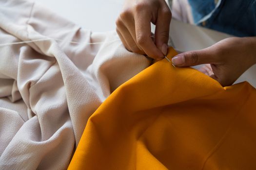 Fashion designer stitching cloth with needle