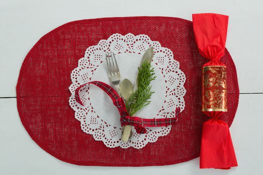 Cutlery with fern tied up with ribbon and chocolate on a placemat