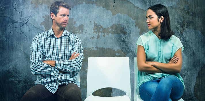 Composite image of displeased couple looking at each other while sitting on chairs