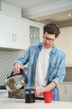 Man pouring coffee from mug into french press