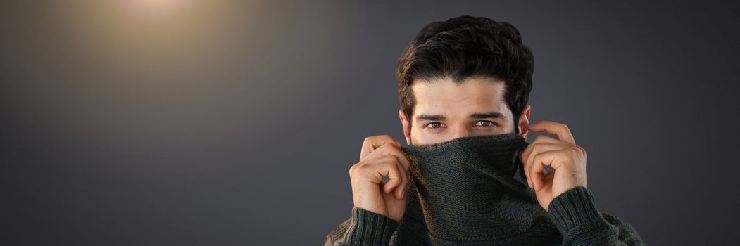 Man hiding under jumper with eyes peering out